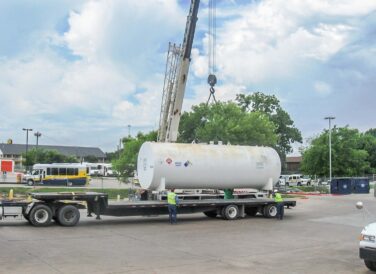 workers next to crane lifting tank for DART environmental project